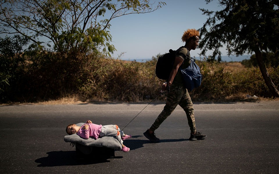 A migrant pulls a girl lying on a cart, following a fire at the Moria camp on the island of Lesbos, Greece, September 11, 2020. REUTERS/Alkis Konstantinidis
